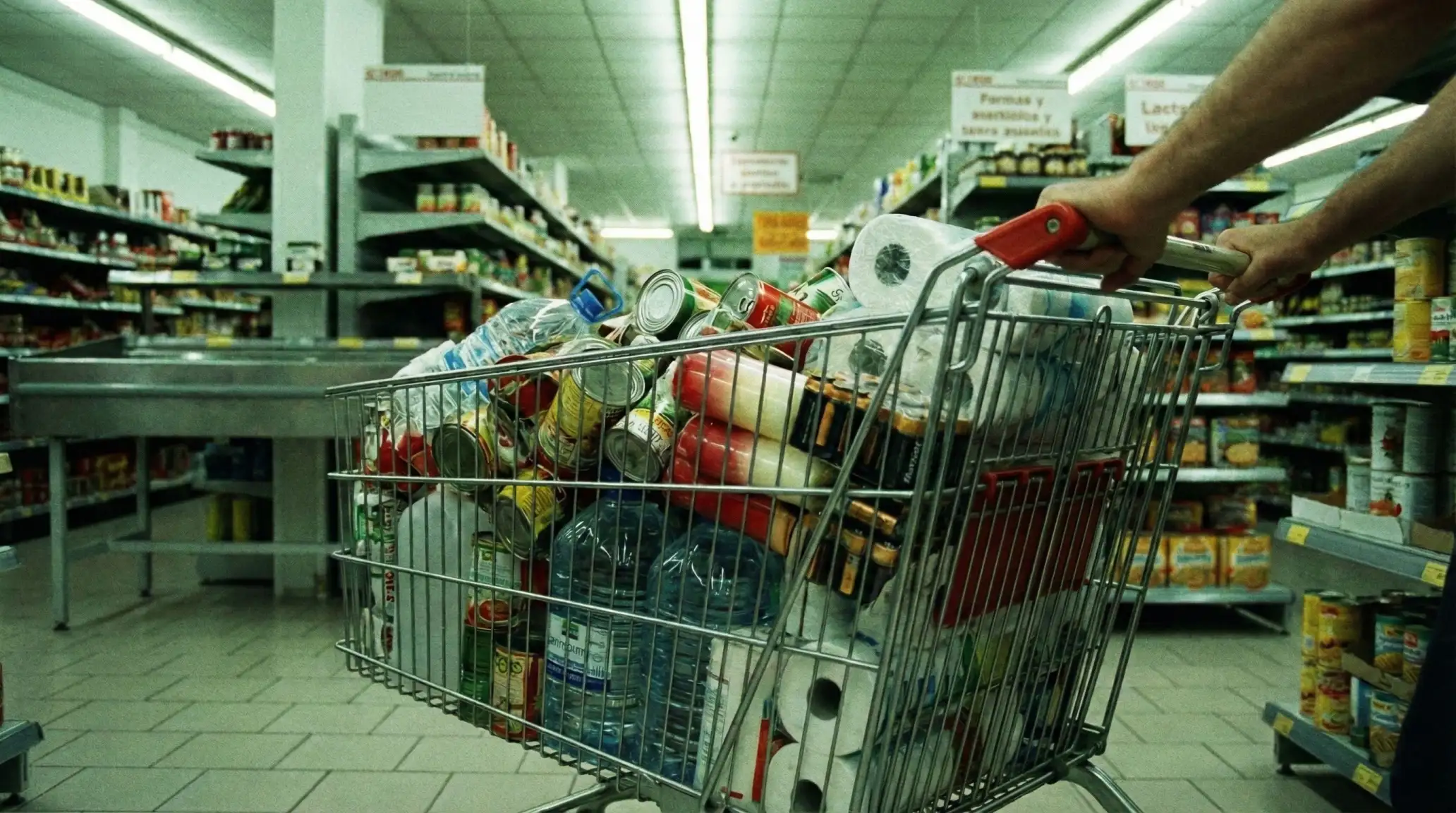 Compras de pánico por el efecto 2000 en supermercado español, latas de conserva y agua.