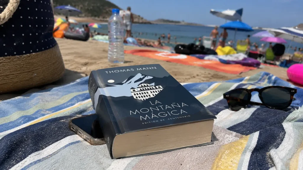LIbro la montaña mágica en la playa sobre una toalla